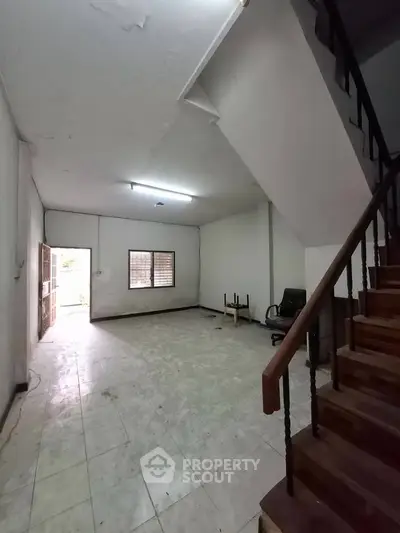 Spacious interior with staircase and tiled flooring, ideal for renovation.