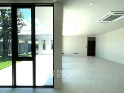 Spacious modern living room with large windows and garden view, perfect for natural light lovers.