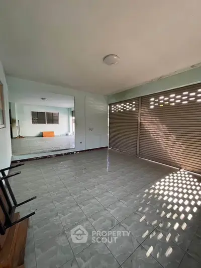 Spacious tiled room with large windows and ample natural light, perfect for versatile use.