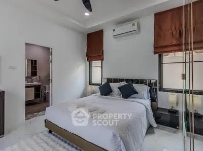 Modern bedroom with ensuite bathroom, featuring elegant decor and natural light.