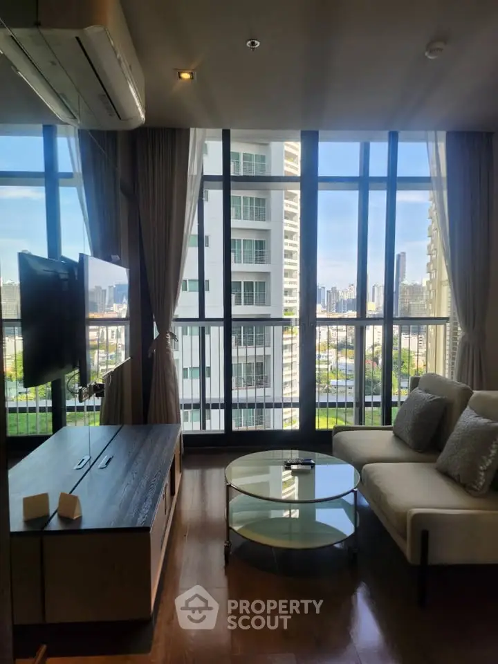 Modern living room with large windows and city view in high-rise apartment.