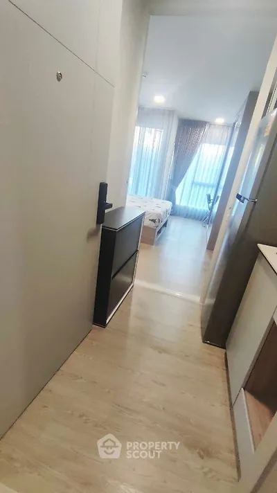 Modern apartment entrance leading to a cozy bedroom with large windows and stylish decor.