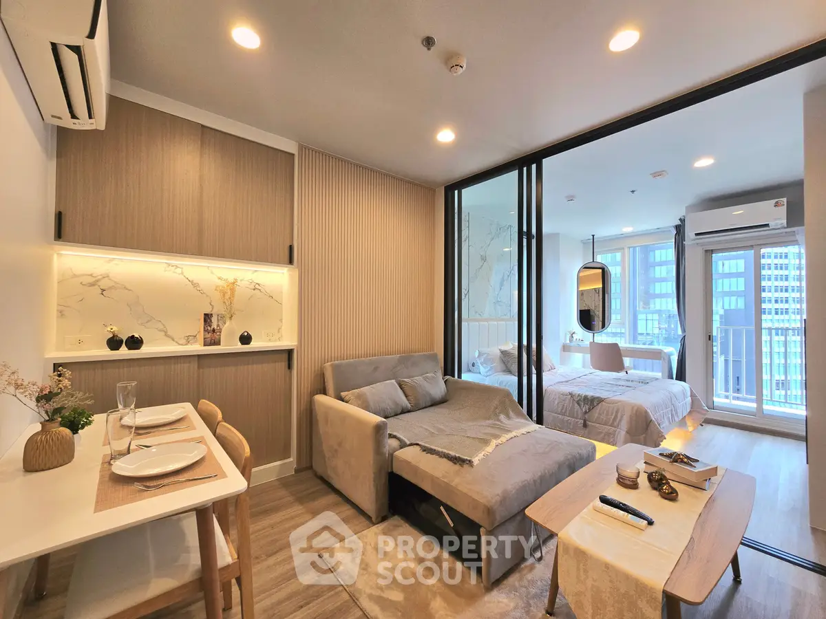 Modern open-plan living room with cozy sofa and stylish dining area in a chic apartment.