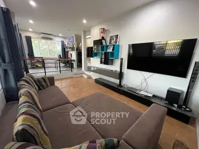 Spacious living room with modern decor and entertainment setup, featuring a large sofa and wall-mounted TV.