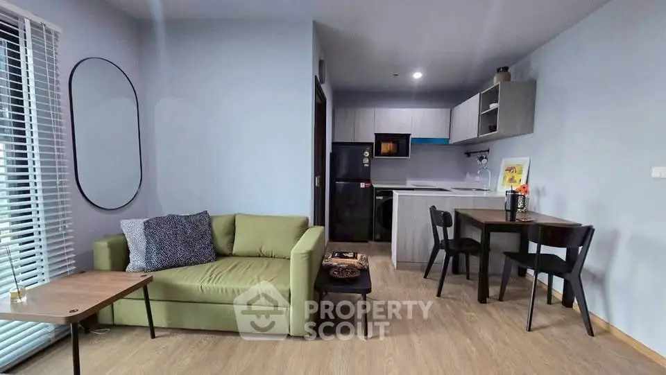 Modern living room with open kitchen, featuring stylish furniture and natural light.