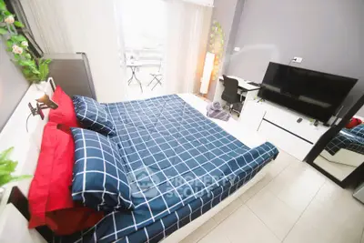 Modern bedroom with stylish decor and large TV, featuring a cozy bed and workspace.