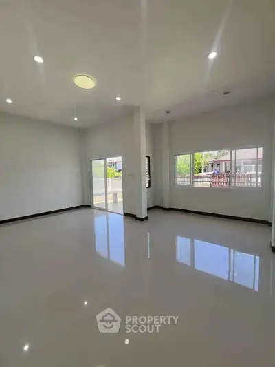 Spacious and bright living room with large windows and glossy floors