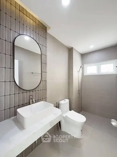 Modern bathroom with sleek design, featuring a large mirror, stylish sink, and contemporary shower area.