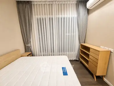 Modern bedroom with minimalist design, featuring a comfortable bed, wooden dresser, and elegant curtains.