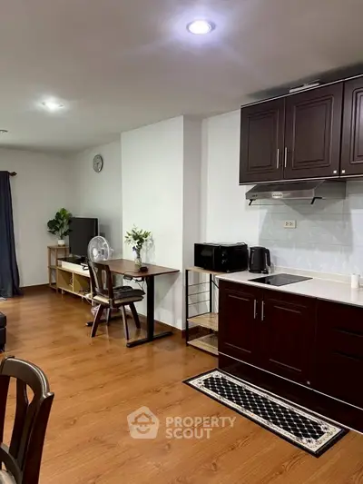 Spacious living area with modern kitchen and wooden flooring in a cozy apartment.