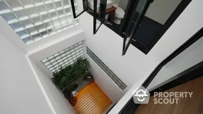 Modern home interior showcasing a high ceiling entryway with sleek black accents and a cozy sitting area, perfect for urban living.