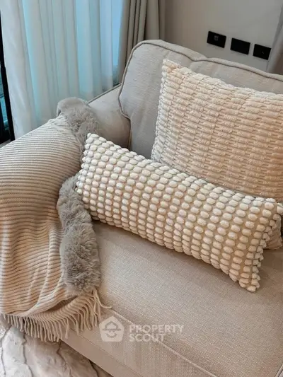 Cozy living room with textured cushions and soft throw on a beige sofa, perfect for relaxation.