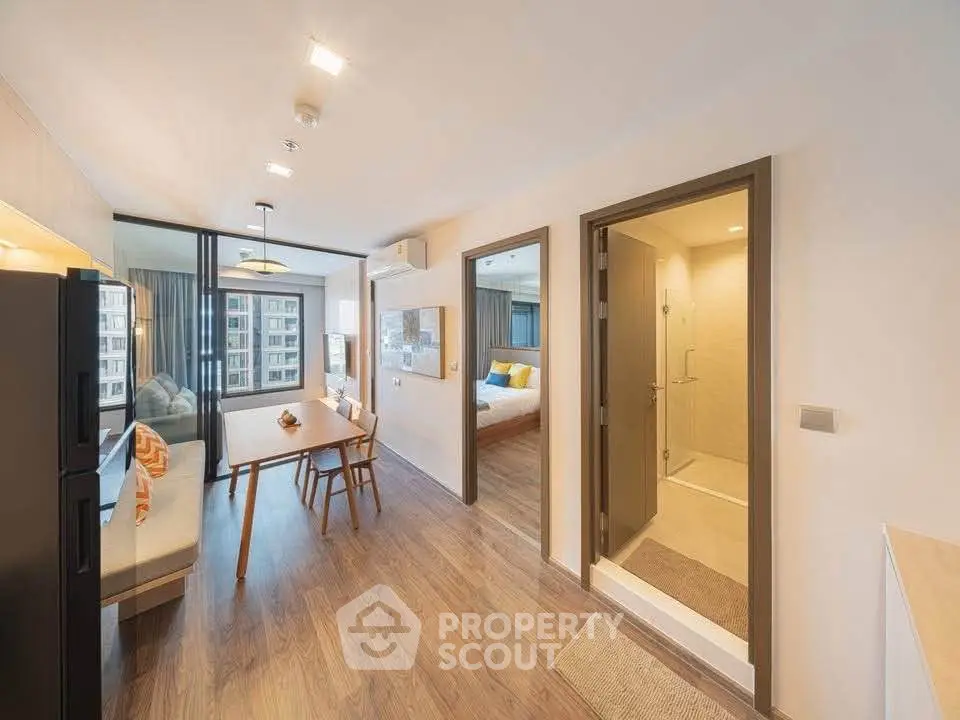 Modern open-plan apartment with dining area, living room, and bedroom, featuring sleek design and ample natural light.