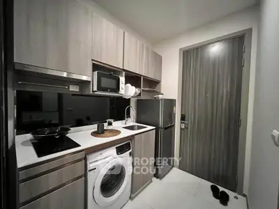 Modern compact kitchen with washing machine and sleek appliances in stylish apartment.