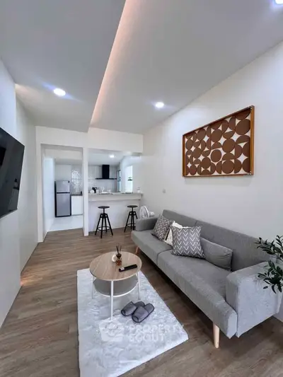 Modern living room with stylish decor and open kitchen layout, featuring cozy seating and contemporary design.