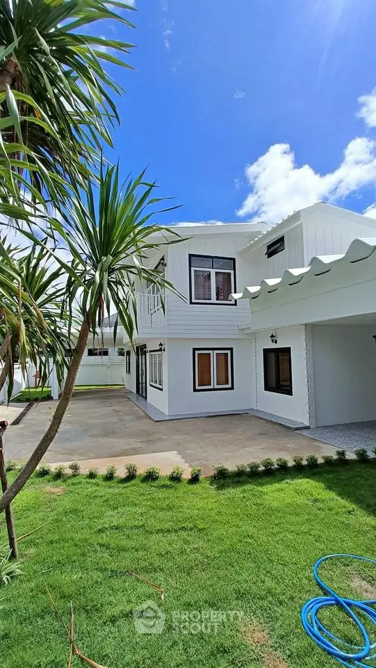 Stunning modern white two-story house with lush green lawn and clear blue sky.