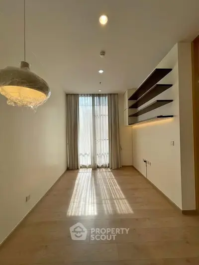 Spacious modern room with large window and elegant shelving, perfect for versatile living space.