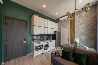 Modern living room with integrated kitchen, featuring sleek appliances and stylish decor.