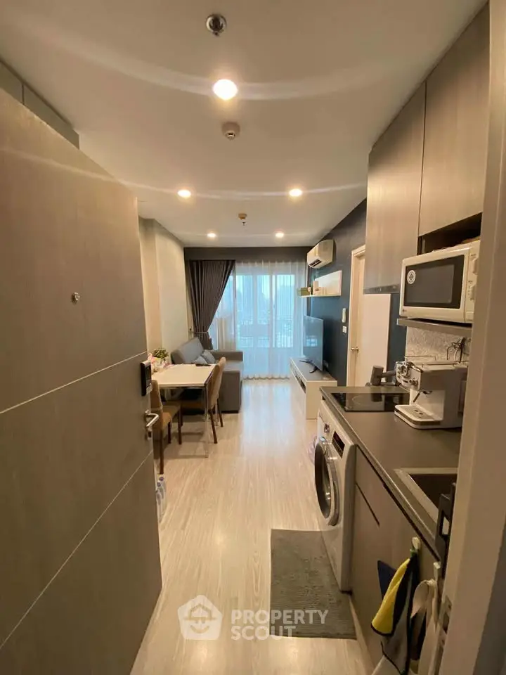 Modern apartment interior with open layout, featuring a cozy living area and kitchen with appliances.