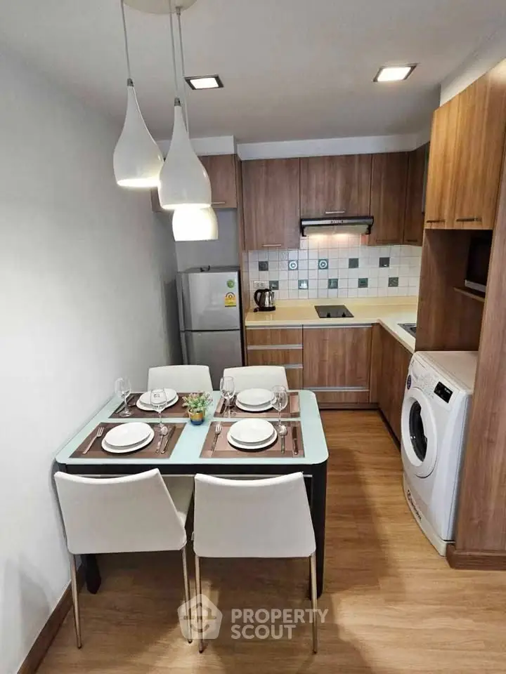 Modern kitchen with dining area, wooden cabinets, and washing machine in a cozy apartment.