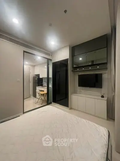Modern bedroom with sleek design and integrated kitchen view, perfect for urban living.