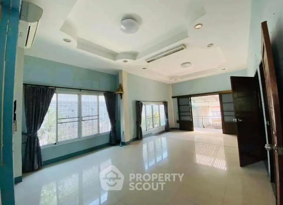 Spacious living room with large windows and modern ceiling design, perfect for natural light and open living.