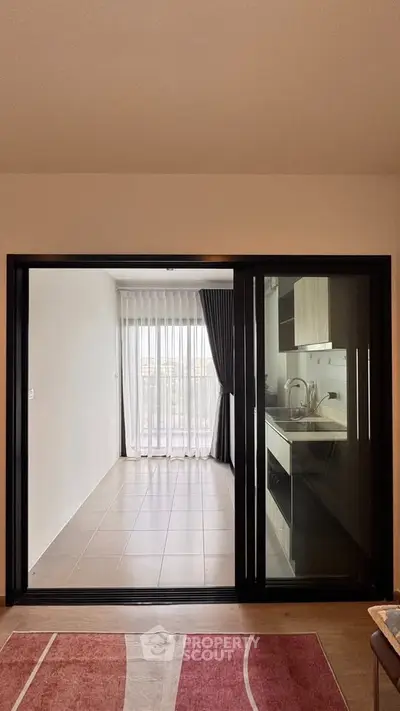 Modern apartment with open kitchen and balcony view, featuring sleek design and natural light.