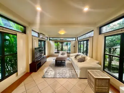 Spacious living room with large windows and garden view, featuring modern furniture and elegant decor.