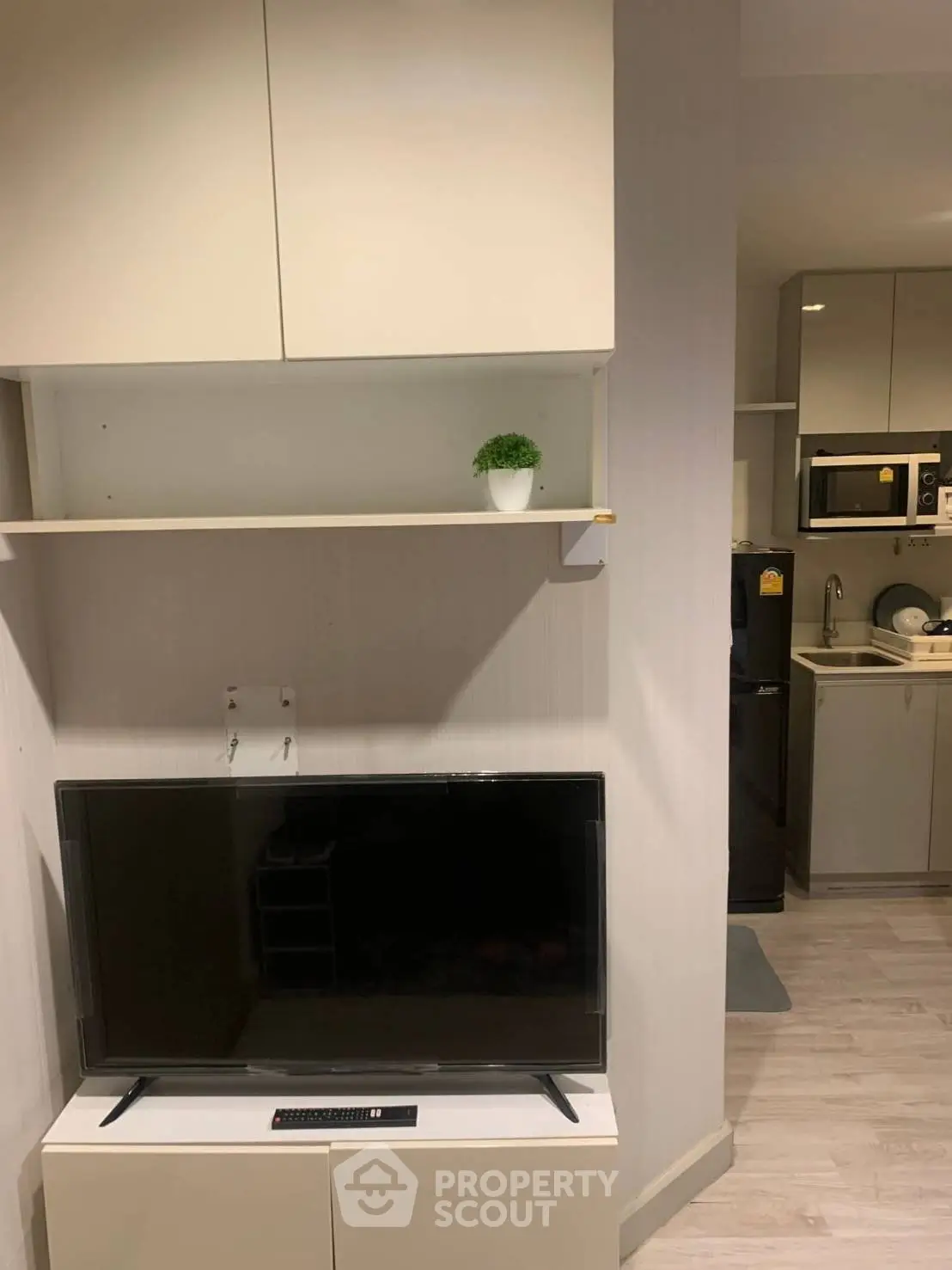 Modern living room with sleek TV setup and compact kitchen area, perfect for urban living.