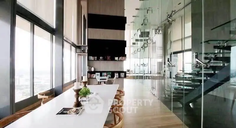 Luxurious modern living room with floor-to-ceiling windows and sleek glass staircase.