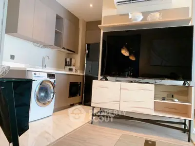 Modern open-plan living room with kitchen, featuring a washing machine and large TV, ideal for urban living.