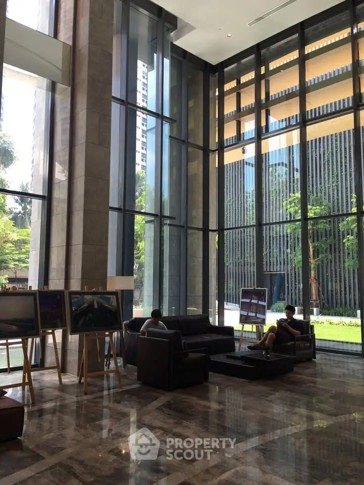 Luxurious building lobby with high ceilings and modern decor, featuring large windows and comfortable seating.