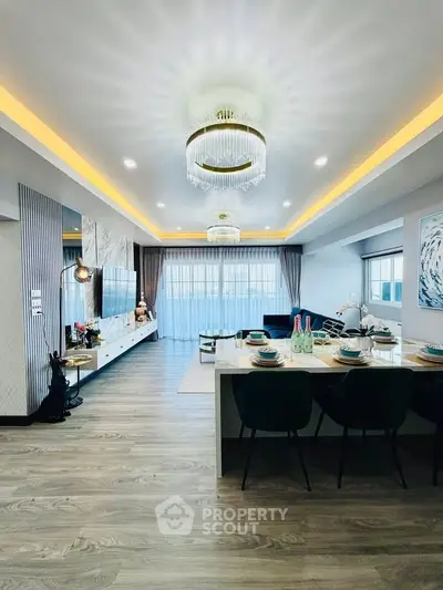 Luxurious modern living room with elegant chandeliers and open dining area, featuring stylish decor and ample natural light.