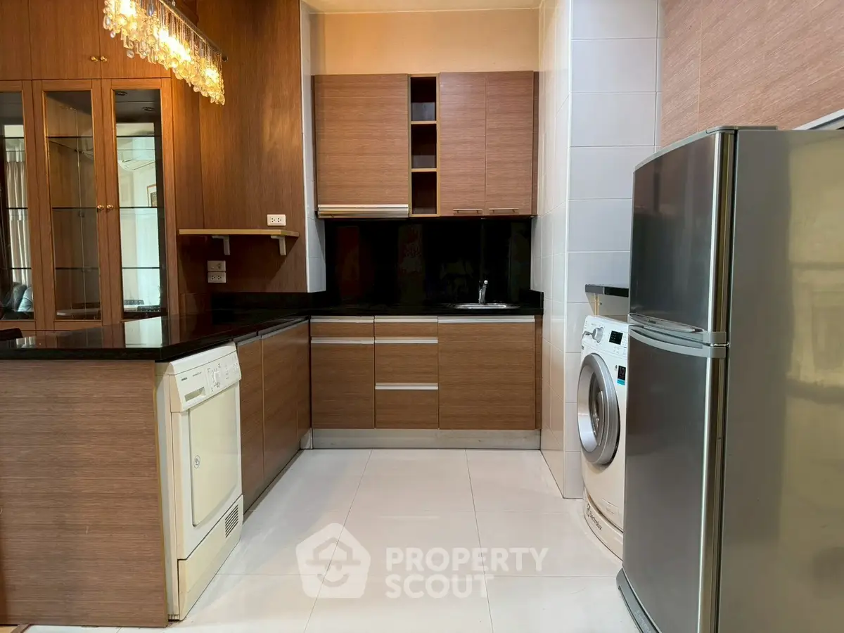 Modern kitchen with wooden cabinets, sleek appliances, and elegant lighting