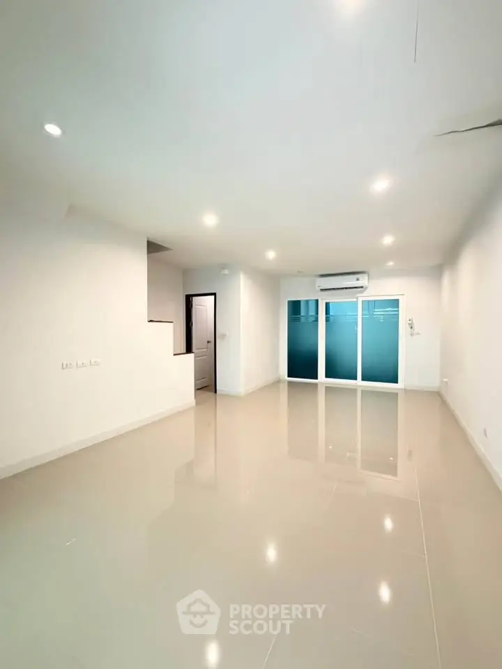 Spacious modern living room with sleek tile flooring and large windows for natural light.