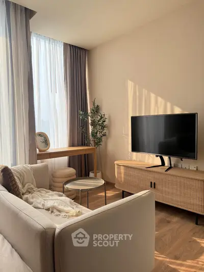 Modern living room with natural light, stylish furniture, and a sleek TV setup.