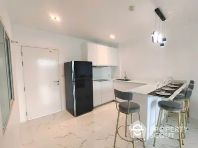 Modern kitchen with sleek black fridge and stylish breakfast bar seating