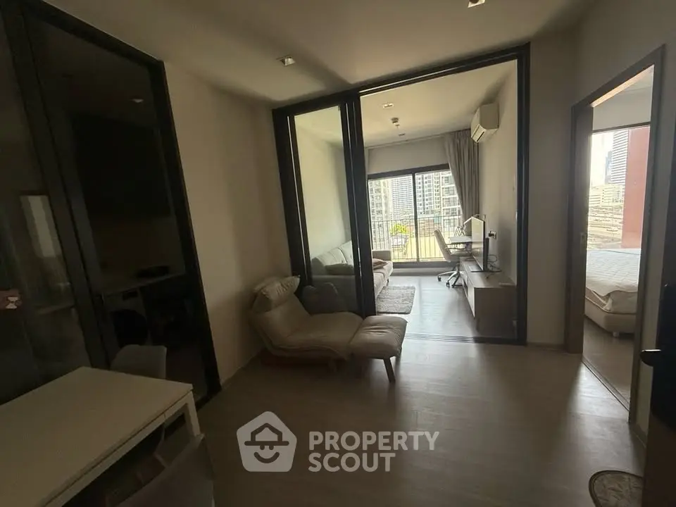 Modern apartment interior with open living room and bedroom, featuring large windows and city view.