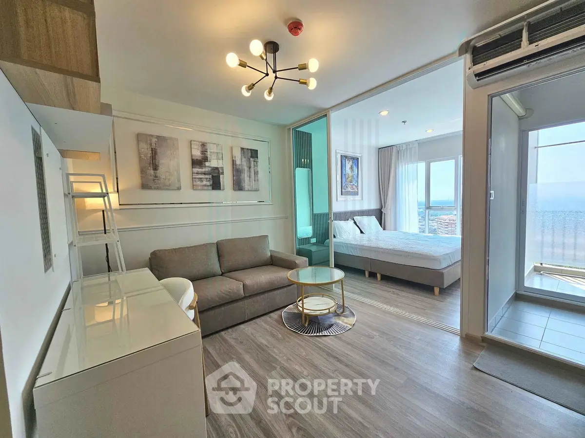 Modern open-plan living room with stylish decor and a view of the bedroom and balcony.