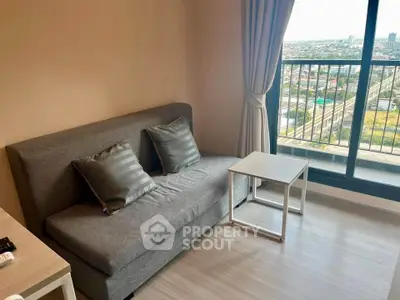 Modern living room with gray sofa and city view from balcony, perfect for urban living.