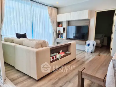 Spacious living room with modern furnishings, large TV, and ample natural light, perfect for comfortable urban living.
