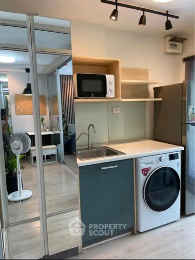 Modern compact kitchen with washing machine and microwave in stylish apartment.