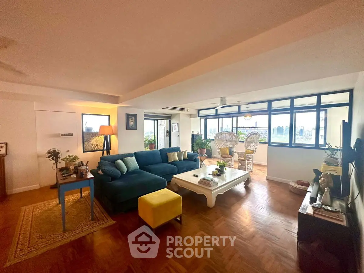 Spacious living room with city view, modern decor, and ample natural light.
