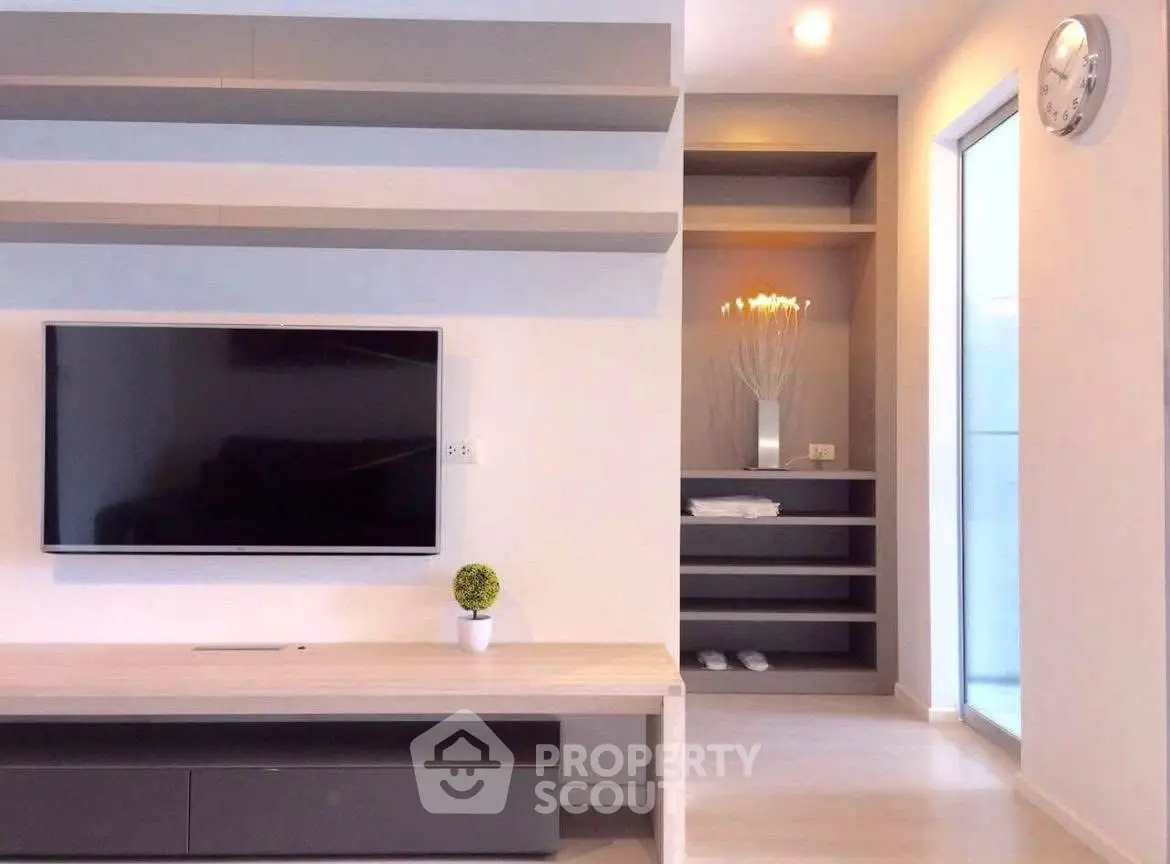 Modern living room with sleek TV setup and stylish shelving in a bright apartment.