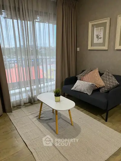 Cozy living room with stylish decor and large window offering natural light.