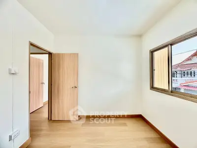 Bright empty room with wooden flooring and large window in modern home