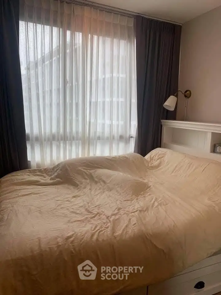 Cozy bedroom with large window and elegant curtains, perfect for relaxation and comfort.