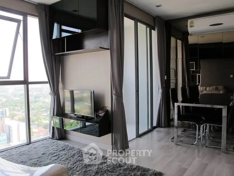 Modern living room with floor-to-ceiling windows and city view, featuring sleek furniture and elegant decor.