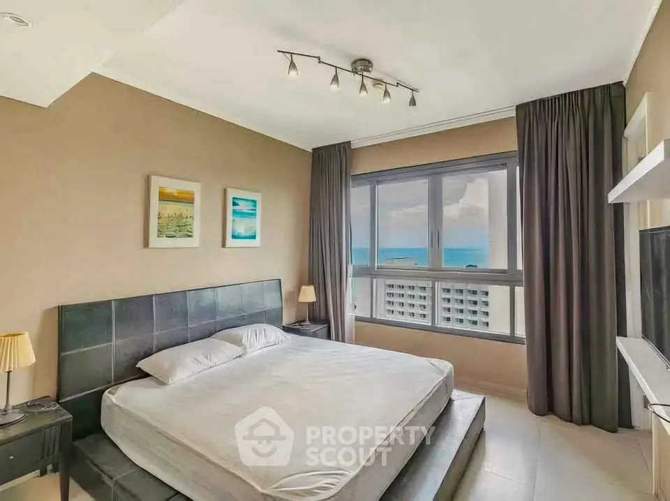 Luxurious bedroom with ocean view, modern decor, and large windows for natural light.