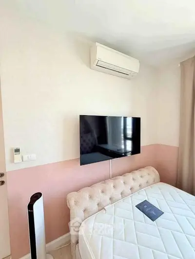 Modern bedroom with wall-mounted TV and air conditioning unit, featuring a stylish bed and soft color palette.